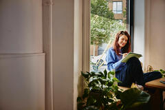 una ragazza che studia seduta sul davanzale di una finestra