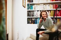 un ragazzo che parla al telefono seduto sulle scale di casa