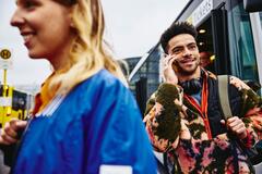 una ragazza di profilo un primo piano e un ragazzo al telefono in un contesto pubblico