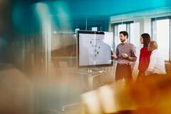 un gruppo di colleghi che lavora su una lavagna interattiva in una stanza a vetri - hr trends & salary survey