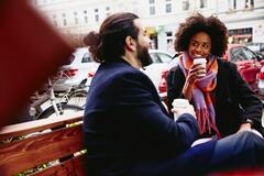 Due persone sedute su una panchina che bevono un bibita
