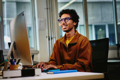 un ragazzo sorridente che lavora al pc 