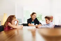 donna che aiuta due bambini a fare i compiti
