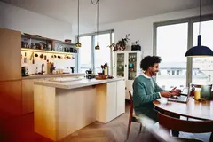 un uomo che partecipa ad un meeting al suo pc, seduto alla scrivania di casa