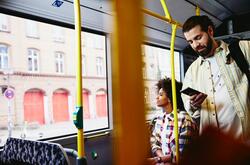 un ragazzo in piedi su un autobus che controlla il telefono - schema turni di lavoro