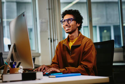 un ragazzo sorridente che lavora al pc 