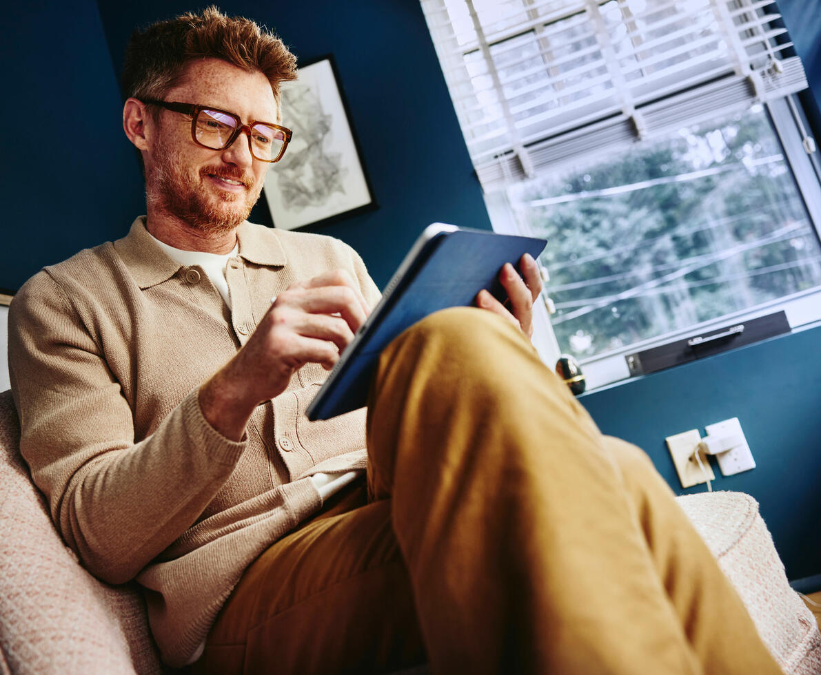 un uomo seduto su una poltrona che consulta il suo tablet