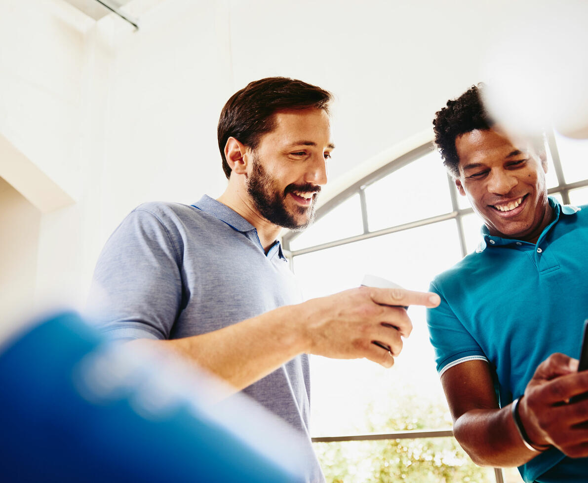 due colleghi che sorridono guardano insieme uno smartphone