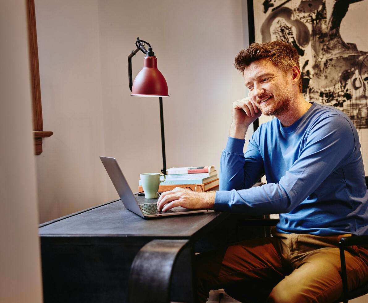 un uomo sorridente che lavora al pc seduto alla scrivania
