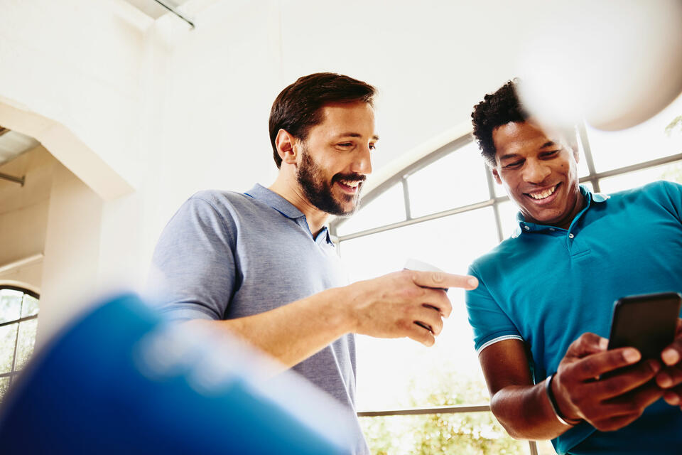 due colleghi che sorridono guardano insieme uno smartphone
