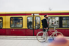 un ragazzo alla banchina del treno che sorregge una bicicletta