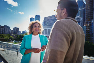 una donna sorridente che parla con un uomo di spalle all'obiettivo su una terrazza