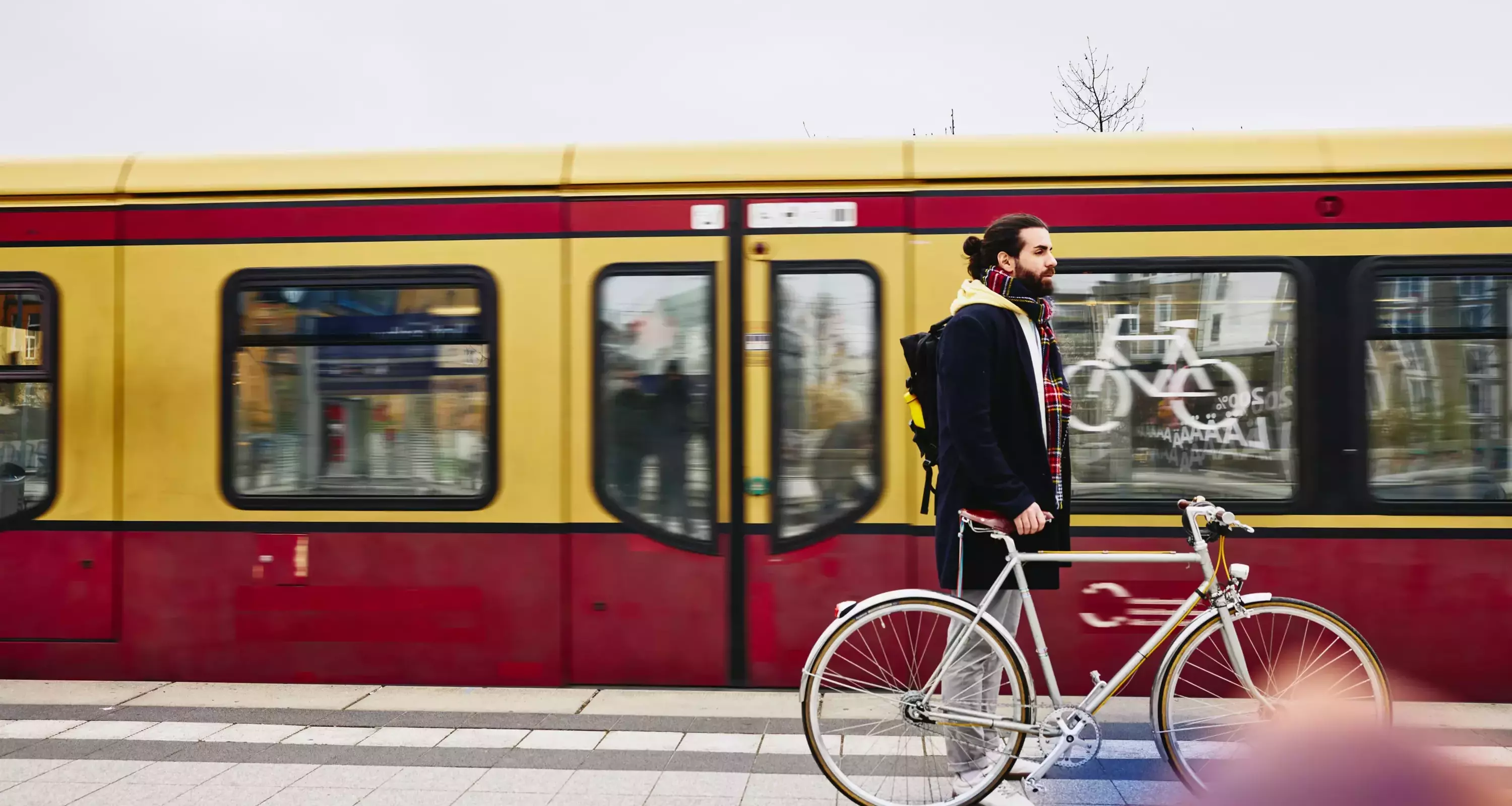 male standing on a train platform with his bike. Train in the background.
